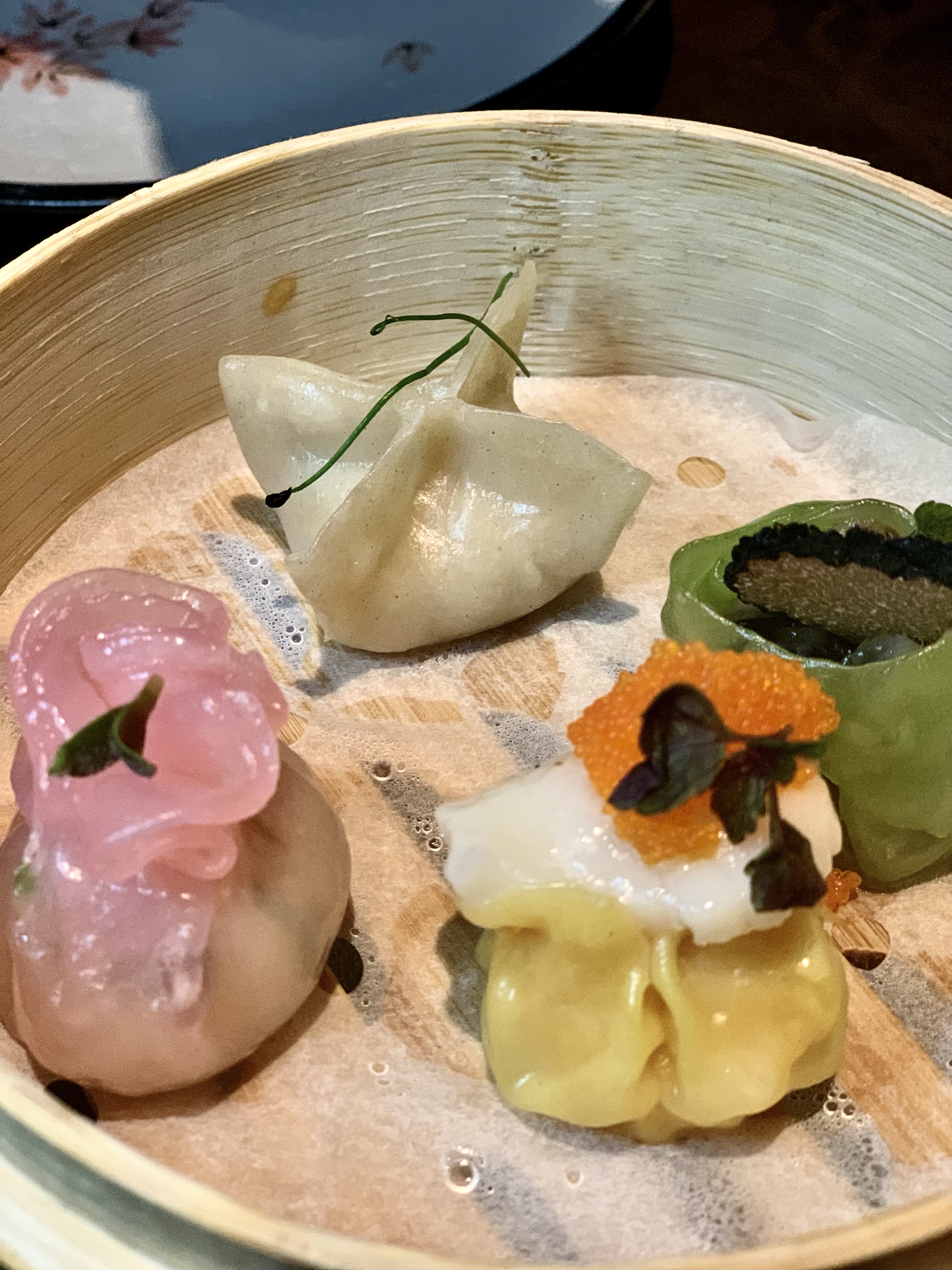 Lulu Wild Birmingham review - a close up of the mixed dim sum starter with pink, yellow and green coloured parcels of food inside a steamer basket. 