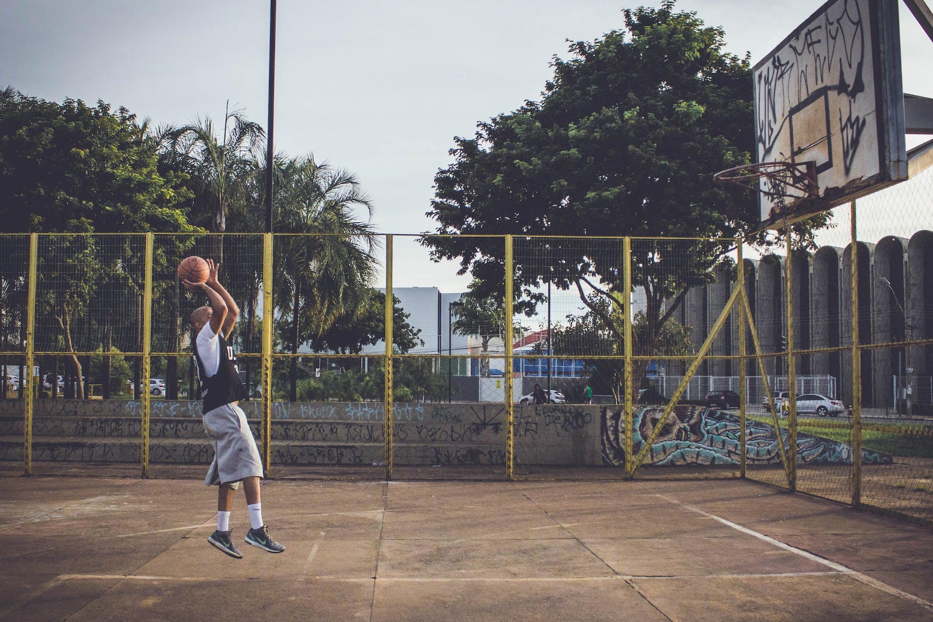 A man dunks a basketball in an outdoor court.