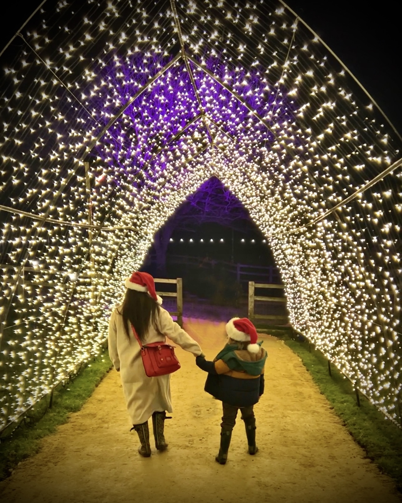 Two children walking through a tunnel of lights.
