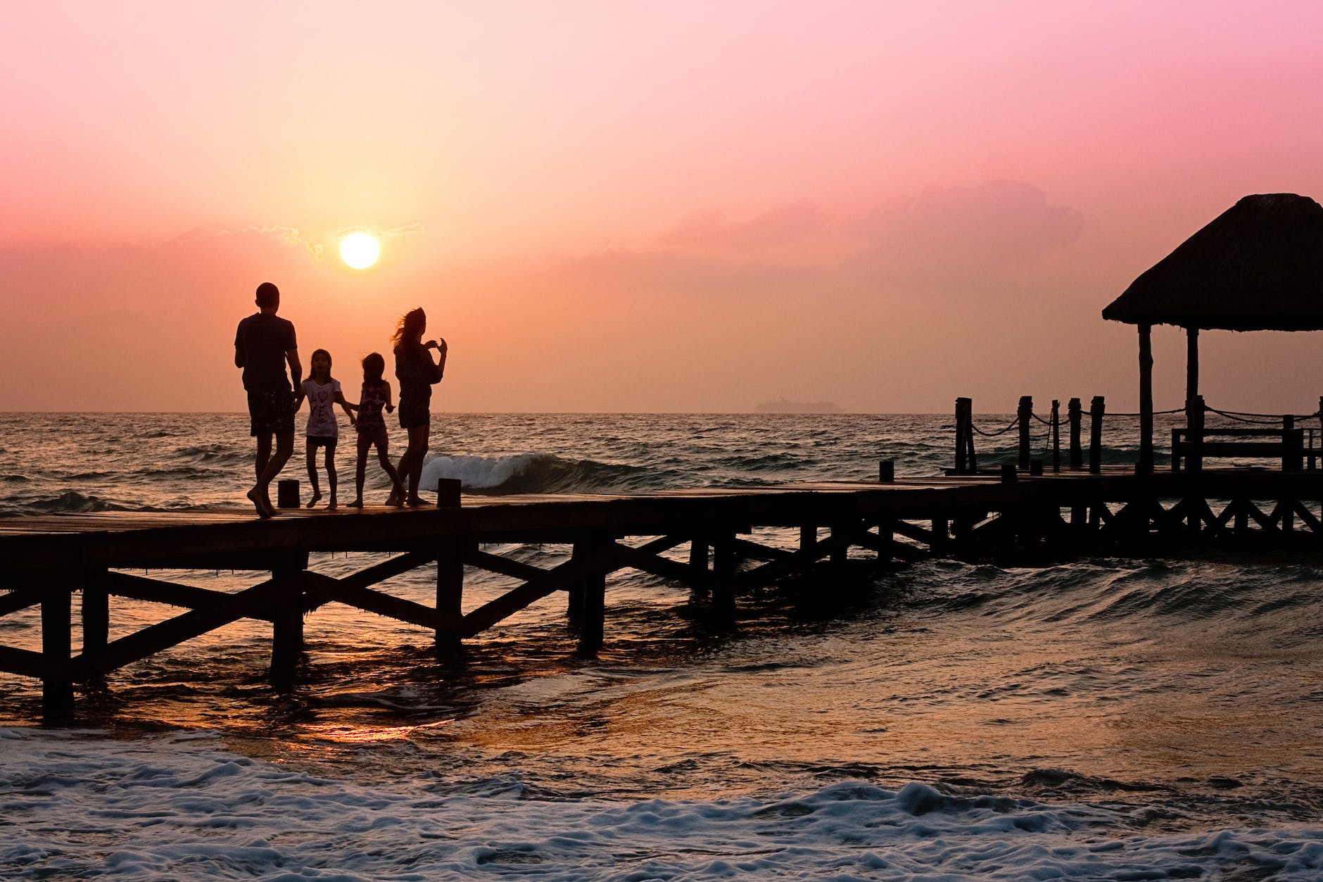A family is walking on a pier at sunset.