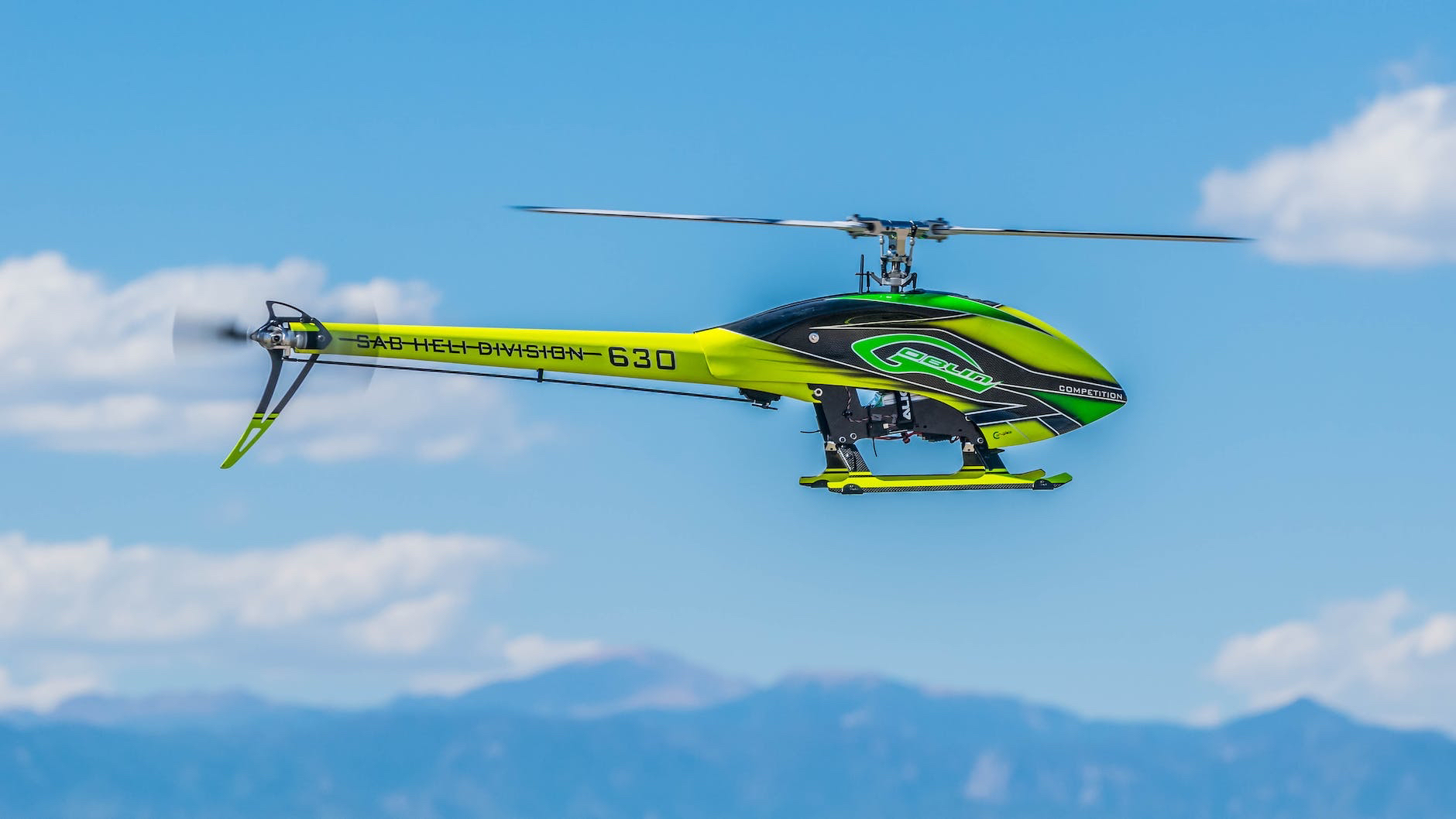 A yellow and green helicopter flying in the air.