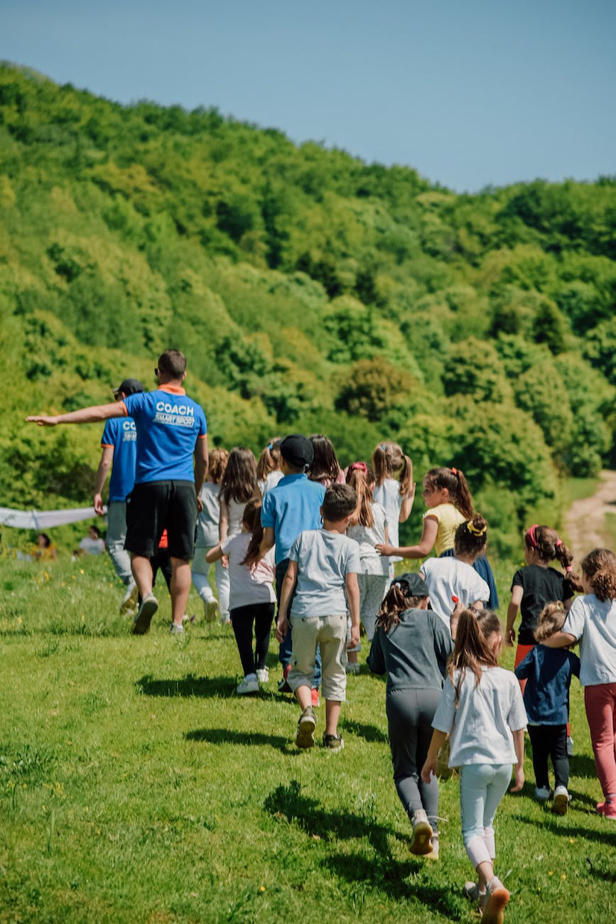 A group of children running on a grassy hill.