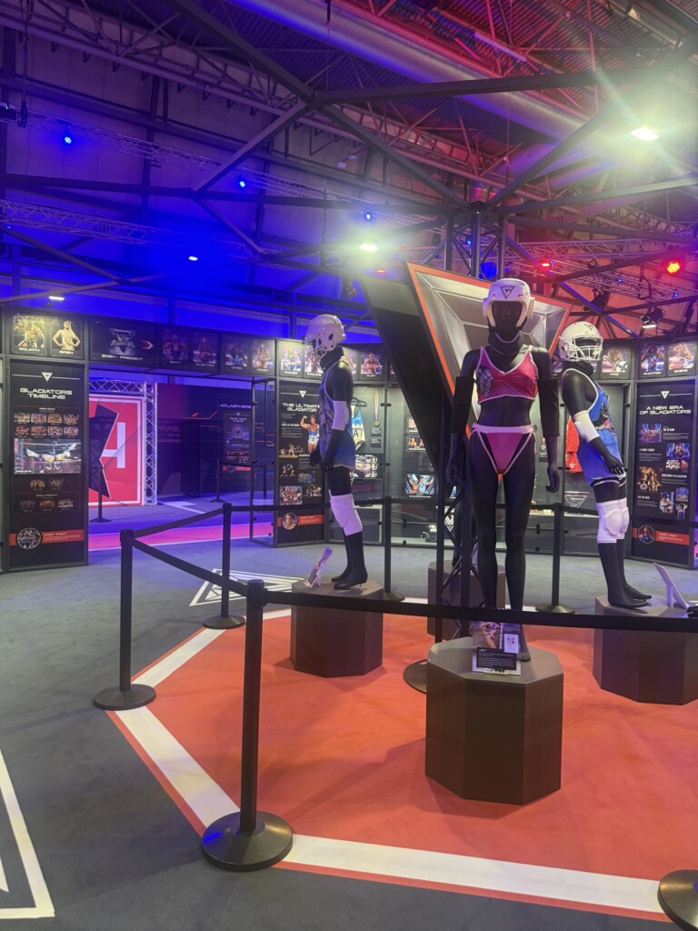 Three mannequins in Power Rangers outfits stand on plinths in a well-lit exhibition, with information panels and photos behind them.